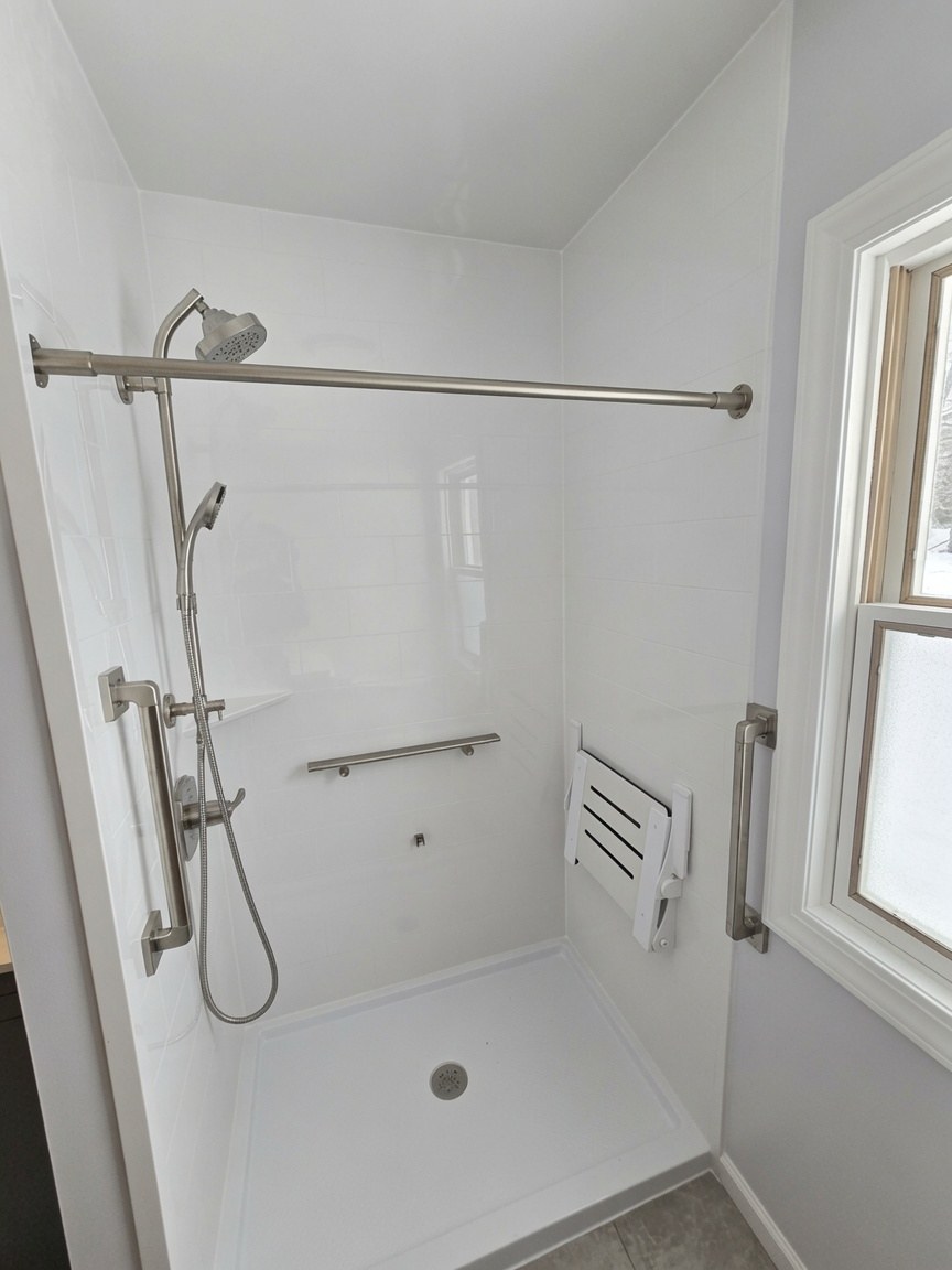Low-threshold white shower with grab bars, handheld, and fold-up seat