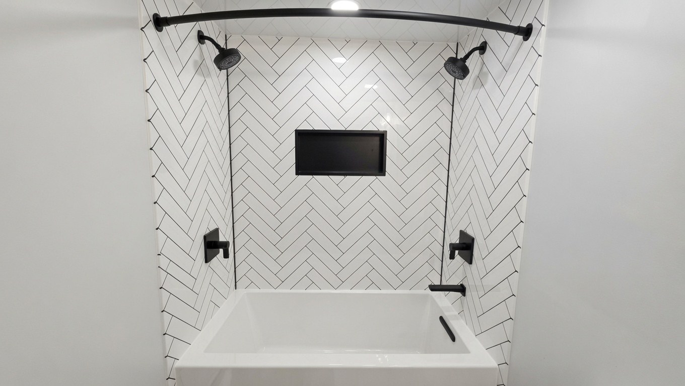 Alcove tub with white herringbone tile, black niche, and dual matte black showerheads