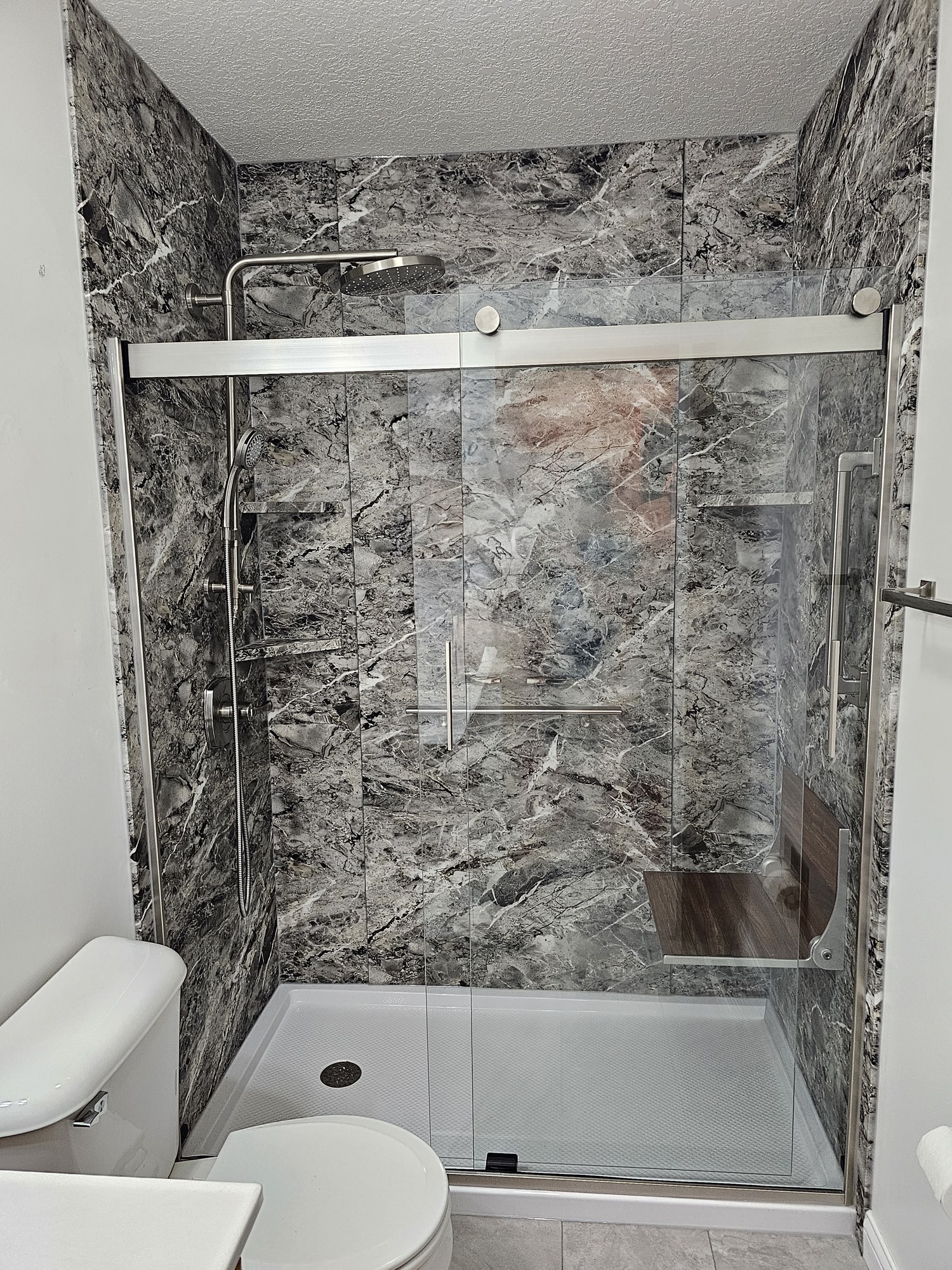 White alcove tub/shower with sliding glass doors and back grab bar
